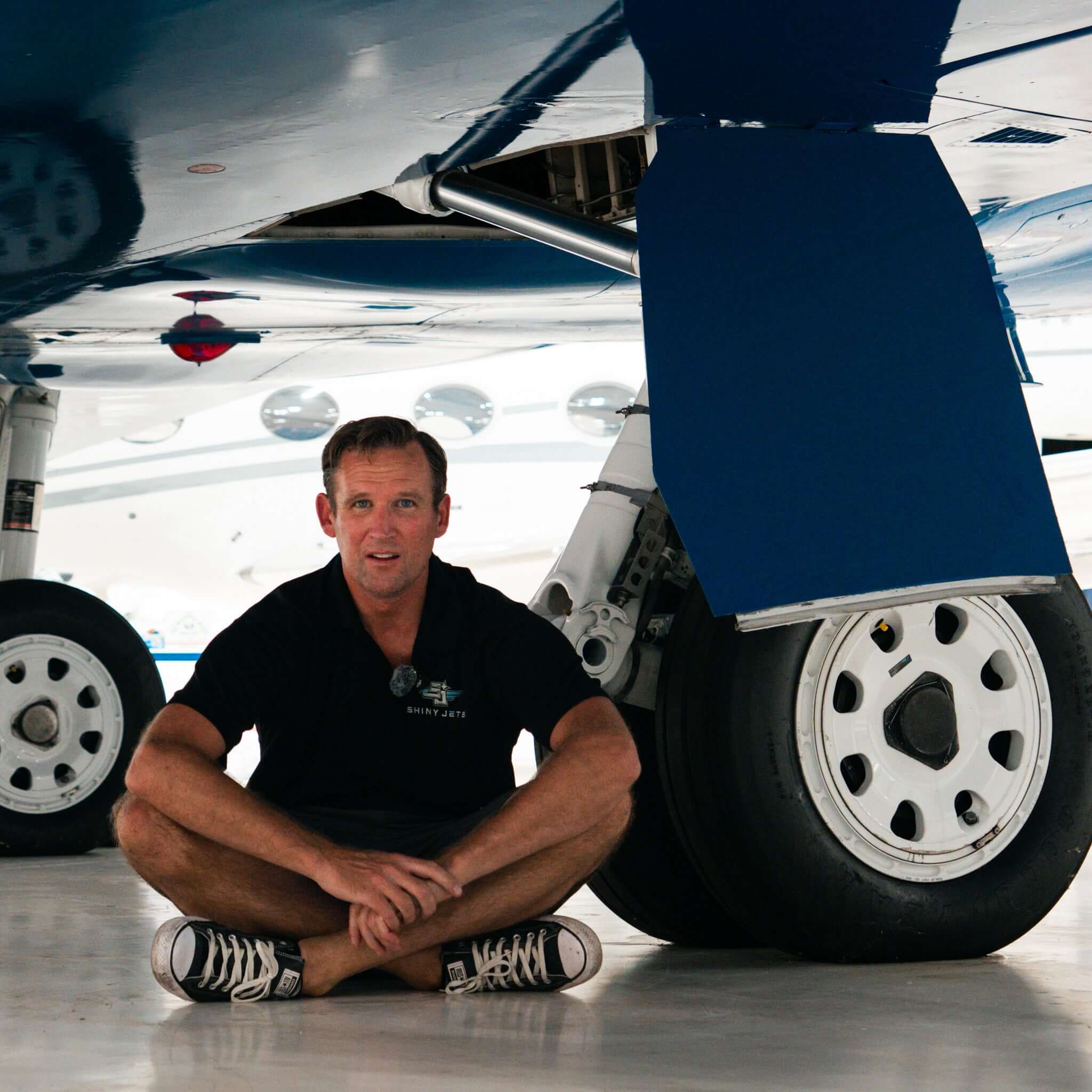 Aircraft detailing expert sitting under private jet landing gear inside hangar, Brett Berry, Shiny Jets, Fly Shiny