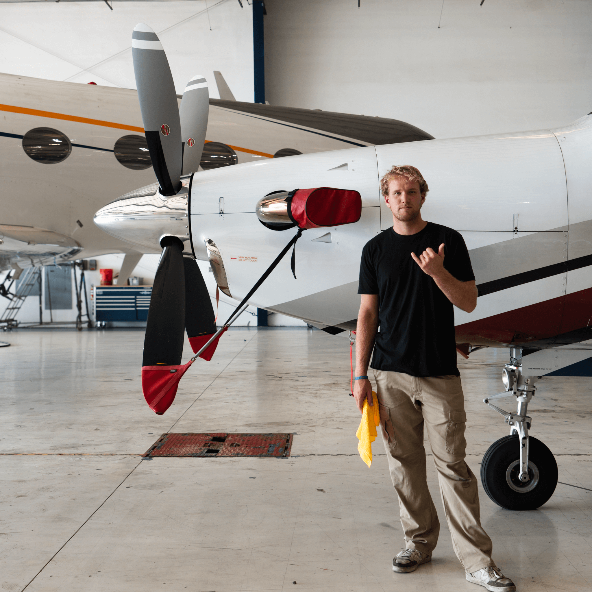 Aircraft detailing technician standing beside airplane inside hangar